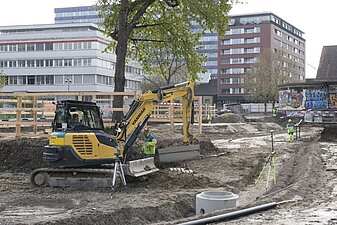 Erdabeiten mit Bagger und zwei Mann.
